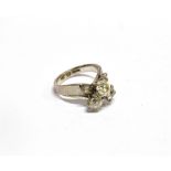 AN ORIENTAL WHITE METAL AND DIAMOND THREE STONE RING BY KEVIN the three off-round old-cut stones