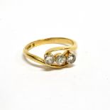 AN EARLY 20TH CENTURY GOLD AND DIAMOND THREE STONE CROSS-OVER RING, the early modern round