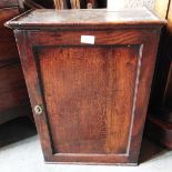 A SMALL OAK WALL CUPBOARD with panelled door opening to drawers and shelves, 45cm wide