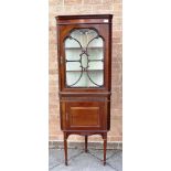 AN EDWARDIAN MAHOGANY CORNER DISPLAY CABINET with blind fret carved decoration, on square tapering