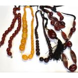 A COLLECTION OF IMITATION-AMBER TO INCLUDE FOUR VARIOUS BEAD NECKLACES AND A LARGE BARREL-SHAPED