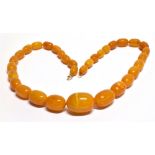 AN EARLY 20TH CENTURY AMBER BEAD NECKLACE the oval beads graduated approx. 32mm x 23mm to approx.