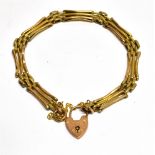 AN EDWARDIAN GOLD THREE-BAR GATE BRACELET With textured-block interlinks and on a padlock clasp,