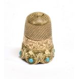 A GOLD & TURQUOISE SET THIMBLE the band decorated with scrolling foliage and a heraldic device