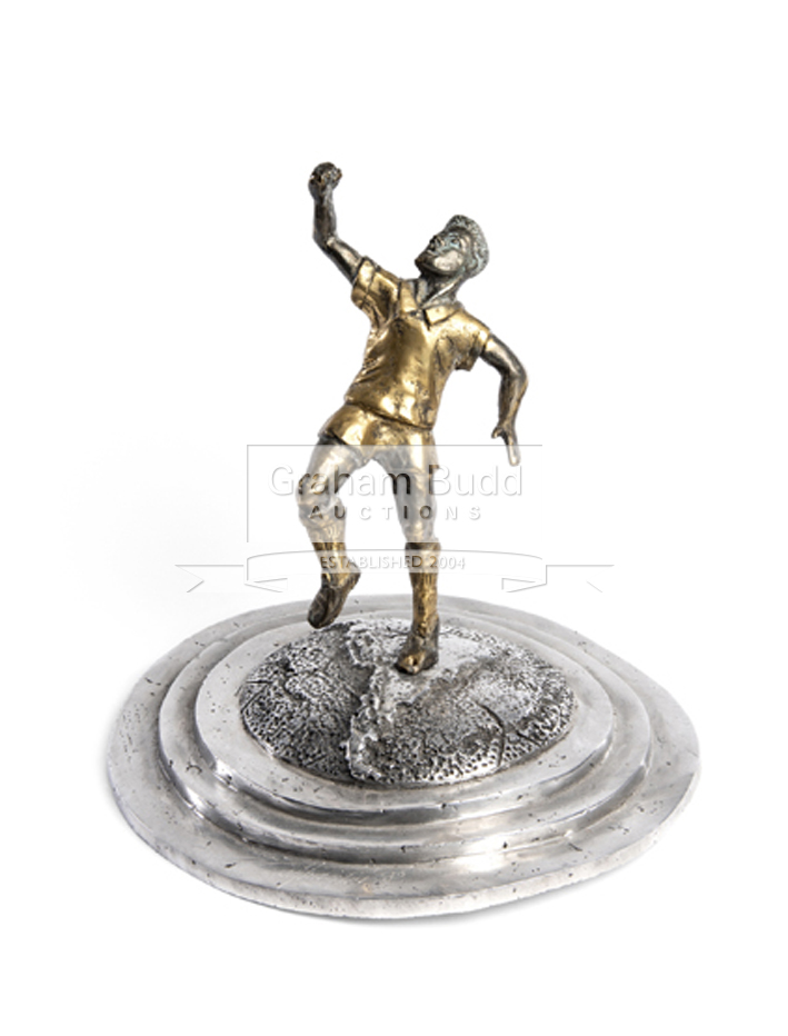 A bronze sculpture of Pele, with one fist raised in the classic post-goal celebratory pose,