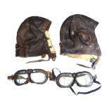 Two World War II RAF brown leather flying helmets and goggles.