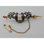 A YELLOW AND WHITE METAL DIAMOND AND RUBY HORSESHOE BROOCH set with both old cut and rose cut