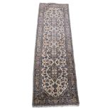 A CREAM GROUND KASHAN RUNNER with four central medallions with floral borders, 298cm x 86cm