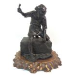 A JAPANESE BRONZE OF A STONE MASON standing over a large stone block with hammer and chisel,