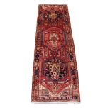 A RED GROUND KARAJEH RUNNER with central lozenges and stylised birds and animals, 330cm x 110cm