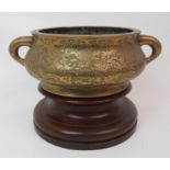 A CHINESE BRASS TWO-HANDLED CENSER engraved allover with dragons, waves and clouds above a key-