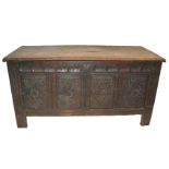 A 19TH CENTURY OAK COFFER the hinged lid above four carved diamond shaped panels and panelled