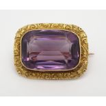 A 15CT GOLD AMETHYST SET BROOCH with floral engraved mount, amethyst approx 2.1cm x 1.5cm,