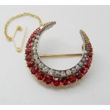 A DIAMOND AND RUBY CRESCENT MOON BROOCH set with estimated approx 0.90cts of old cut diamonds,