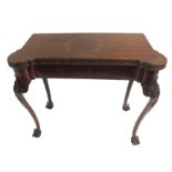 A GEORGE II STYLE MAHOGANY CARD TABLE the shaped top with carved foliate edge enclosing a baize