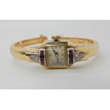 A YELLOW METAL ART DECO STYLE BANGLE WATCH set with diamonds and red gems, Swiss movement, 16