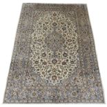 A KASHAN CREAM GROUND RUG with floral designs, central medallion and a border with floral palmettes,