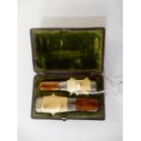 A cased pair of amber and ivory cigar and cigarette holders, each 6.2cm long approx Condition