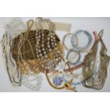 A bag full of vintage costume jewellery to include a beaded skull cap, a carved lucite bangle and