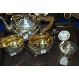 A lot comprising a three piece silver plated tea service, a tea caddy and a travel clock Condition