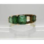 A bright yellow metal five stone emerald ring (one emerald lacking) largest emerald approx 5.7mm x