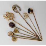 A collection of gold and yellow metal stick pins to include diamond set, garnet, citrine heart and