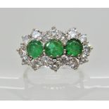 An 18ct white gold emerald and diamond dress ring, each emerald is approximately 4.6mm in diameter