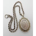 A white metal Victorian locket engraved with flowers, dimensions including bail 6cm x 3.8cm,
