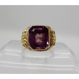 A bright yellow metal gents ring set with a faux amethyst, size U1/2, weight 11.5gms Condition
