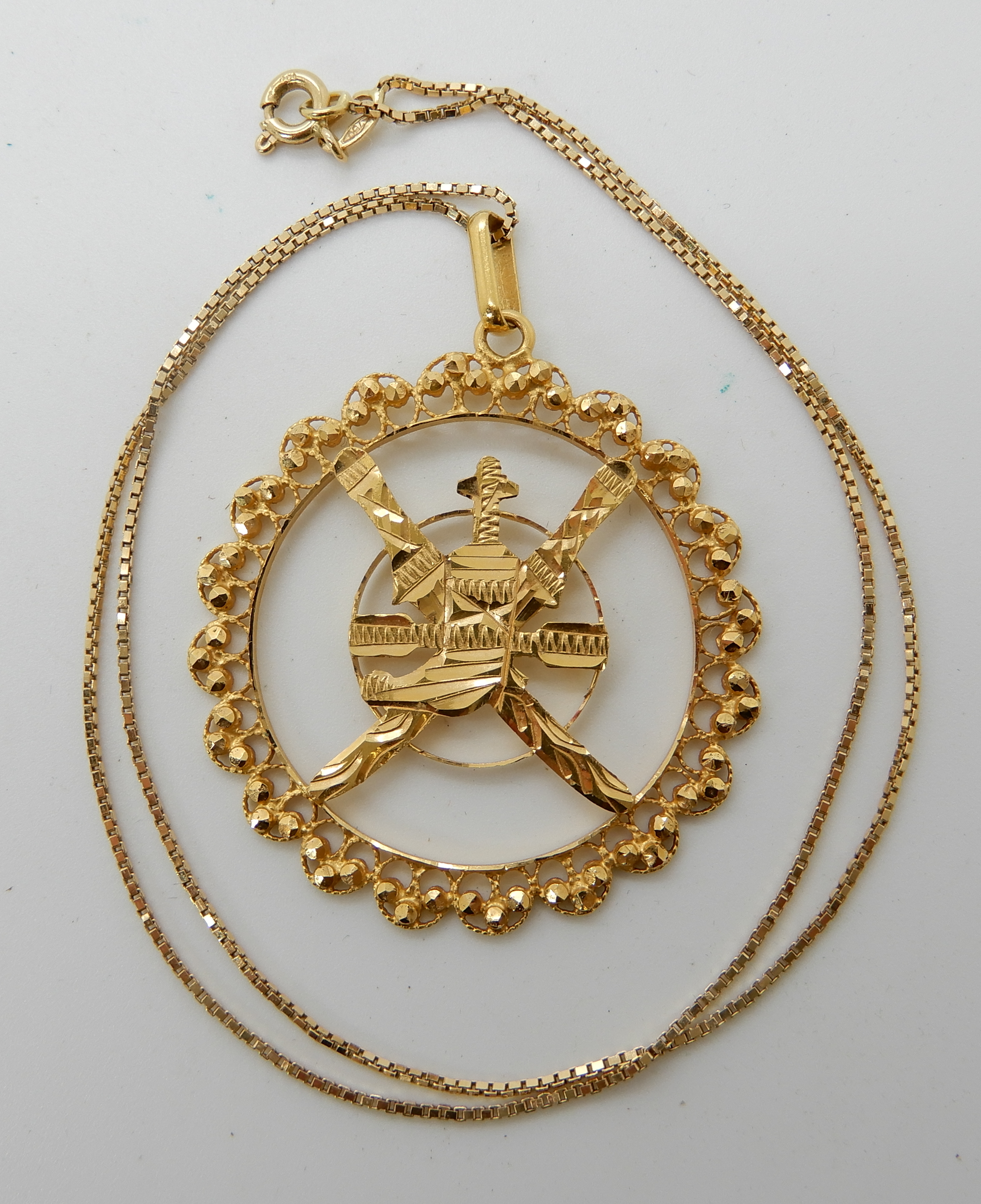 A 21k pendant depicting the National Emblem of Oman, weight 5.6gms, together with a 18ct box chain