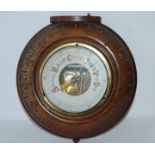 A cased oak circular wall barometer, 21cm and a H.M.S. Vanguard circular metal plaque, 13cm wide (2)