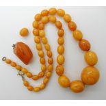 A STRING OF AMBER COLOURED BEADS AND A PENDANT largest bead approx 26mm x 23mm, smallest 7.1mm x 8.