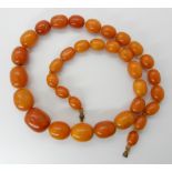 A STRING OF AMBER COLOURED BEADS largest bead approx 25mm x 20.2cm, smallest bead 14.5cm x 11mm,
