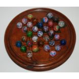 A COLLECTION OF VICTORIAN MARBLES approx 2cm diameter on turned wood solitaire board, 24cm