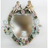 A CONTINENTAL HEART SHAPED WALL MIRROR decorated with two putti holding a swag of flowers, with