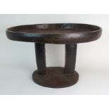 *WITHDRAWN* AN AFRICAN TRIBAL HARDWOOD CIRCULAR TABLE with deep carved rim above a pair of curved