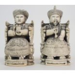 A PAIR OF CHINESE CARVED IVORY EMPEROR AND CONSORT each seated on a throne chair and wearing