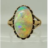 AN 18CT GOLD OPAL RING in scalloped galleried mount, with fleur de lis shoulders. Dimensions of