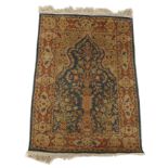 A PERSIAN SILK AND COTTON RUG with a tree of life emanating from a vase on pedestal with a floral