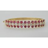 A 14K GOLD DIAMOND AND RUBY BANGLE set with estimated approx 2.40cts of brilliant cut diamonds