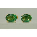 A PAIR OF BRIGHT YELLOW METAL MOUNTED EMERALD STUD EARRINGS emeralds approx 7.1mm x 5.1mm, in four