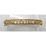 A CONTINENTAL BRIGHT YELLOW METAL ROSE CUT DIAMOND BANGLE with galleried mount and three strand