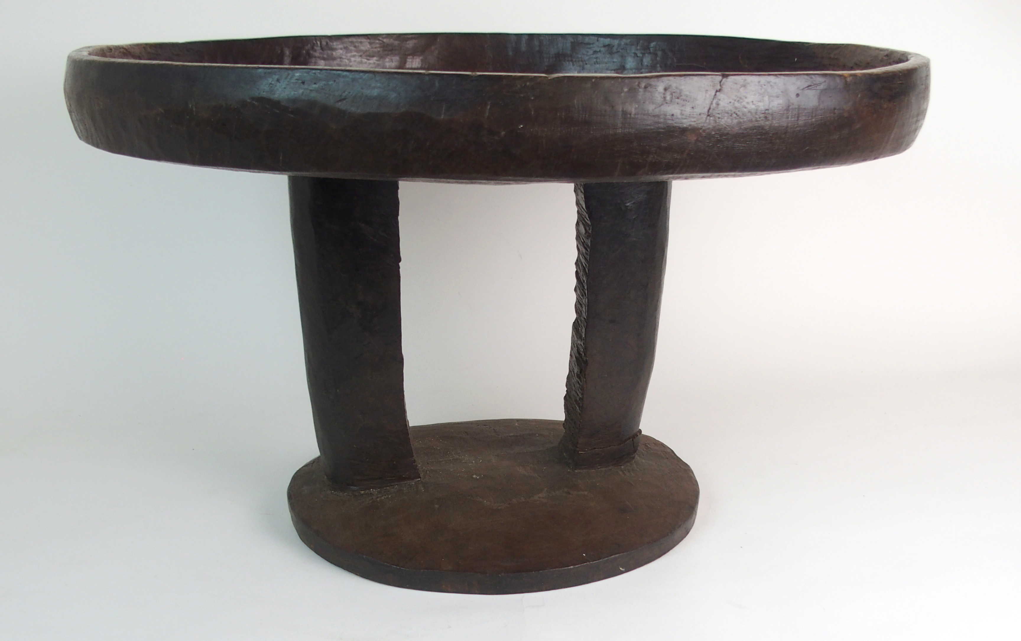 *WITHDRAWN* AN AFRICAN TRIBAL HARDWOOD CIRCULAR TABLE with deep carved rim above a pair of curved - Image 3 of 8