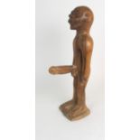 AN AFRICAN MALE FERTILITY FIGURE carved with large phallus and standing on a mound base, 44cm high