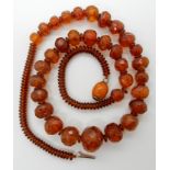 A STRING OF AMBER COLOURED BEADS facet cut of slightly freeform shapes, largest bead approx 19.4mm x