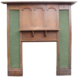 AN OAK ARTS AND CRAFTS FIRE SURROUND with over-hanging dentil cornice above scroll framed panels and