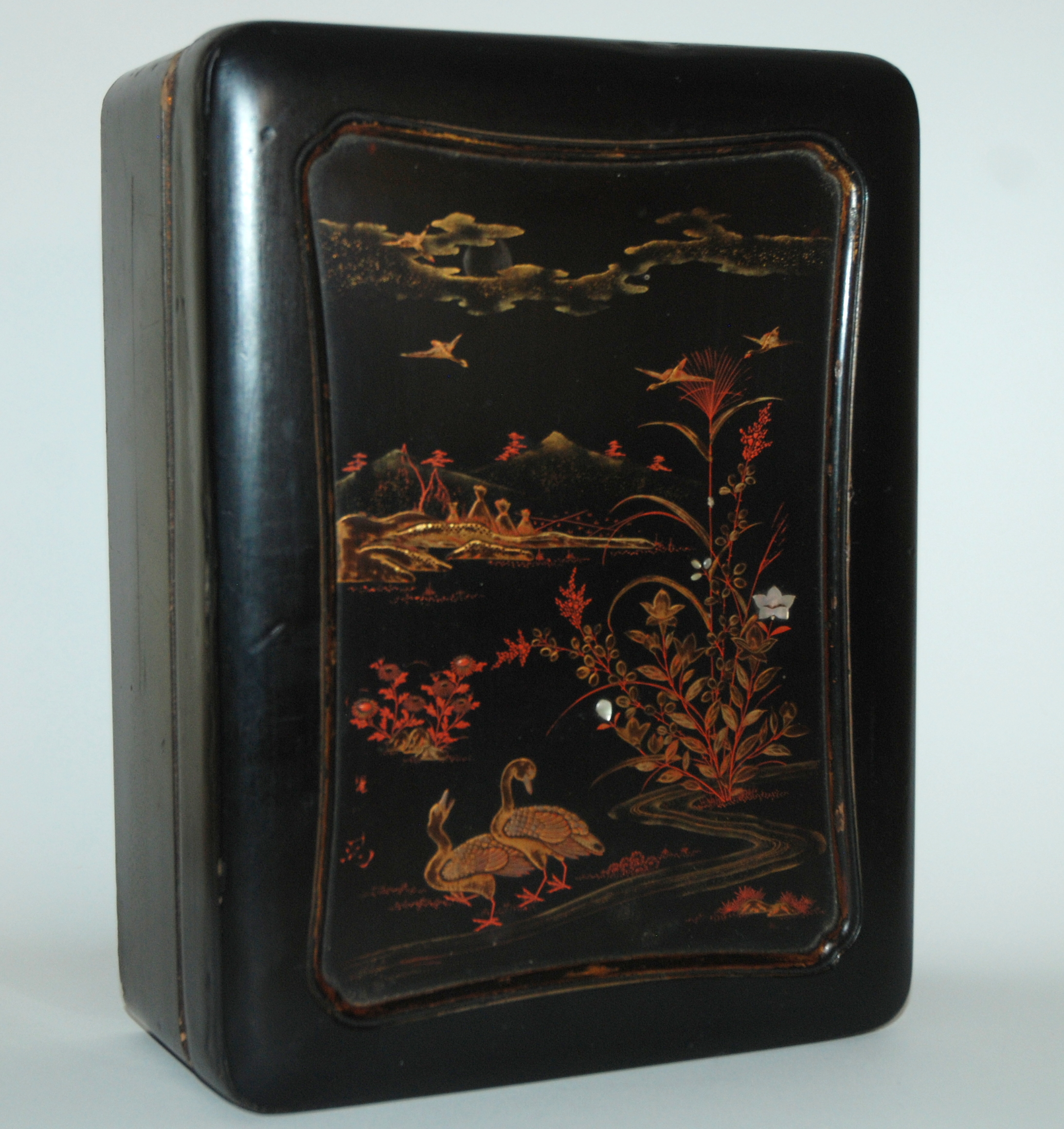 A CHINESE BLACK LACQUERED GAMES BOX the cover decorated with birds and flowers in a river landscape,