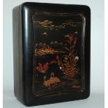 A CHINESE BLACK LACQUERED GAMES BOX the cover decorated with birds and flowers in a river landscape,