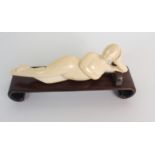 A CHINESE CARVED IVORY MEDICINE LADY the reclining nude with hand on head and breast, wearing a pair
