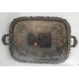 A silver plated twin handled serving tray with foliate decoration on four scrolling feet, 71cm